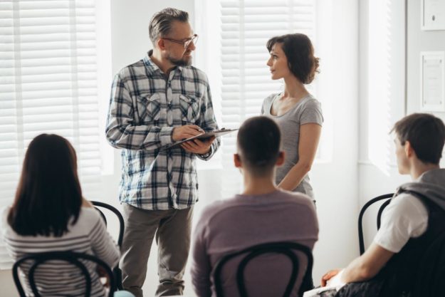 How Long Is A Detox Program_ A woman asking a man with a clipboard, "How long is detox?"