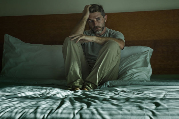 addiction and your physical health (3) man sitting up in bed concerned about Addiction and Your Physical Health