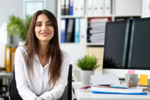 woman smiling at her desk after going to the alcohol detox center