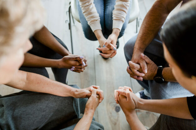 A group of people engaged in an AA prayer
