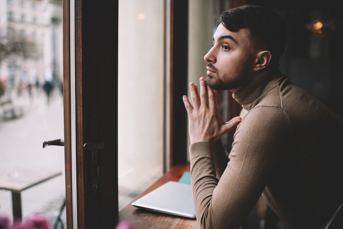 Man looking out window pensive
