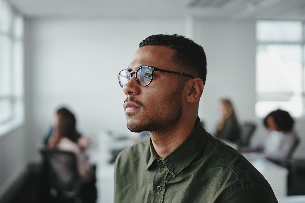 Man with glasses looking off into the distance thinking